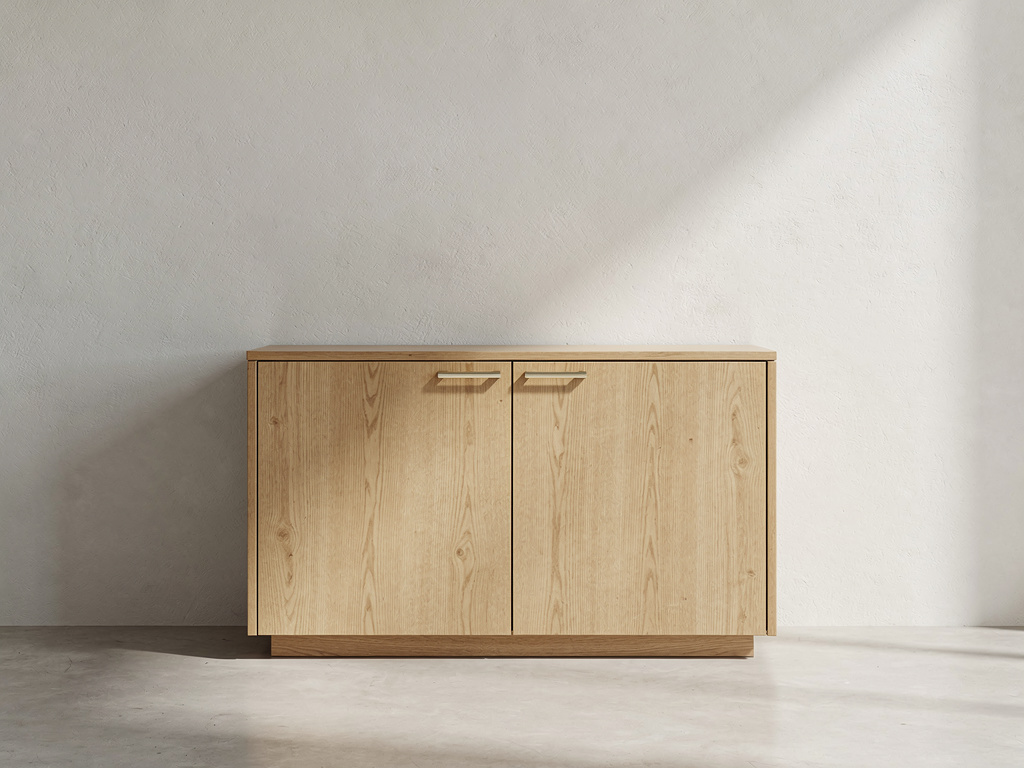 A custom oak cabinet with slim brass handles standing against a plain plaster wall.
